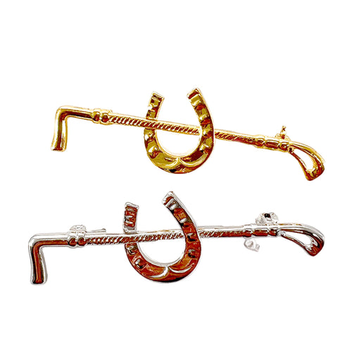 Two gold and silver horseshoe brooches on a white background